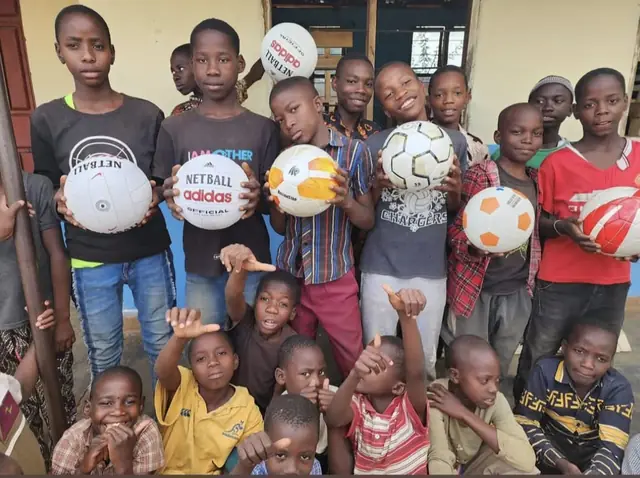 Children holding new footballs and netballs