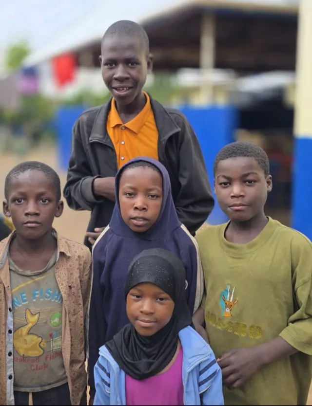 Five children standing together at the centre
