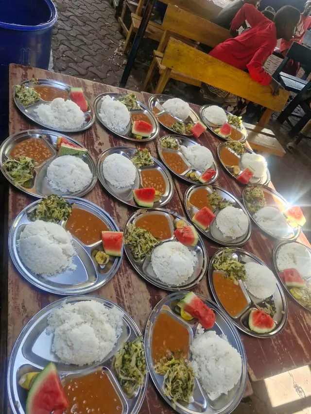 Plates of rice, beans, greens and watermelon ready for lunch