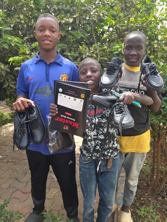 Boys proudly holding new school shoes
